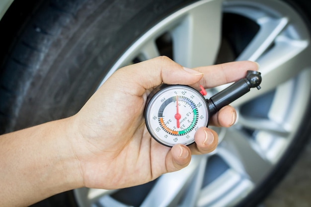 Photo cropped hand holding pressure gauge by car wheel