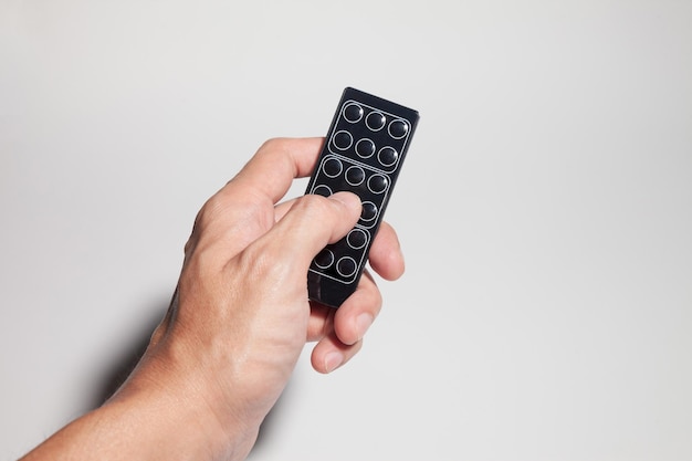 Photo cropped hand holding remote control against white background