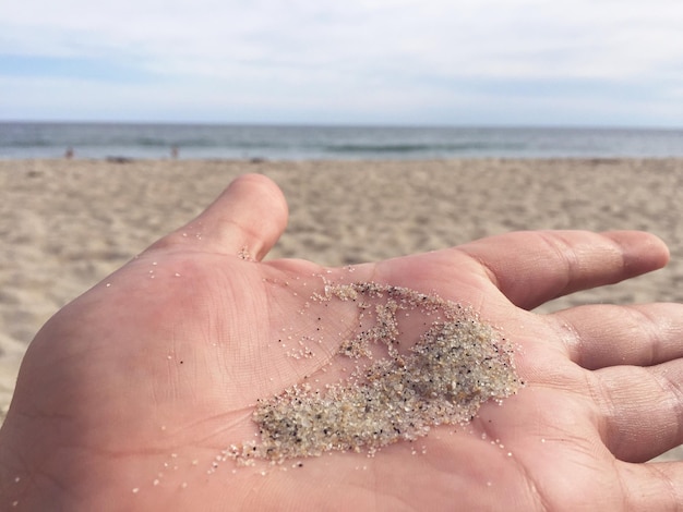 Фото Рука, держащая песок на пляже