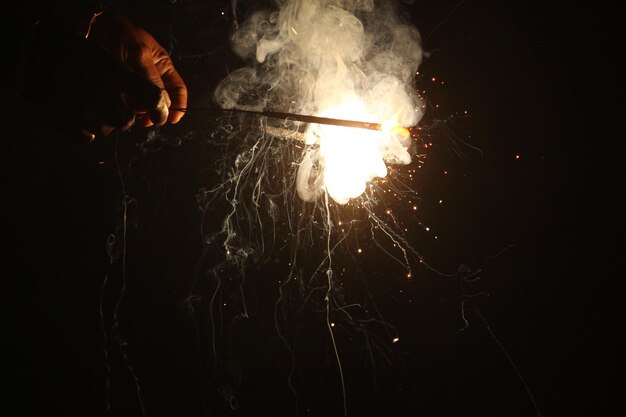 Photo cropped hand holding sparkler burning at night