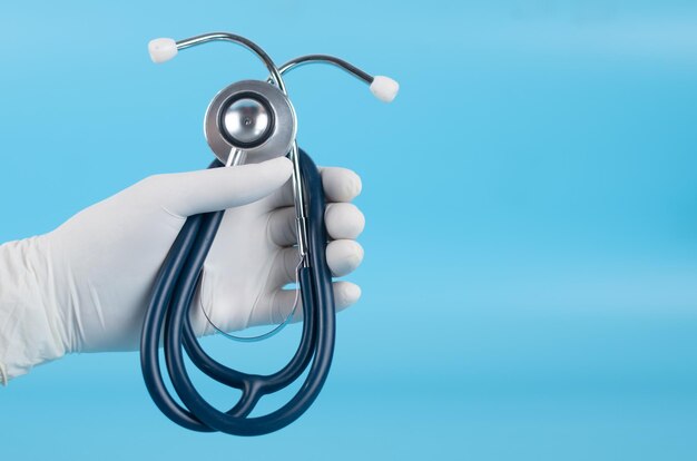 Cropped hand holding stethoscope against blue background