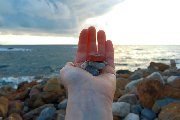 Foto mano tagliata che tiene le pietre sulla spiaggia