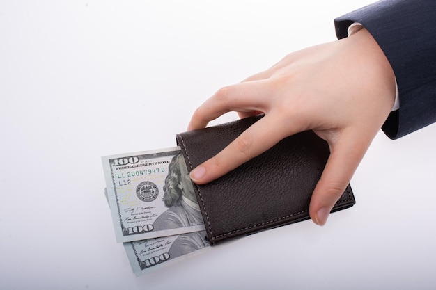 cropped hand holding wallet with banknote against white background