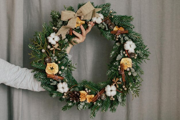 Photo cropped hand holding wreath against curtain