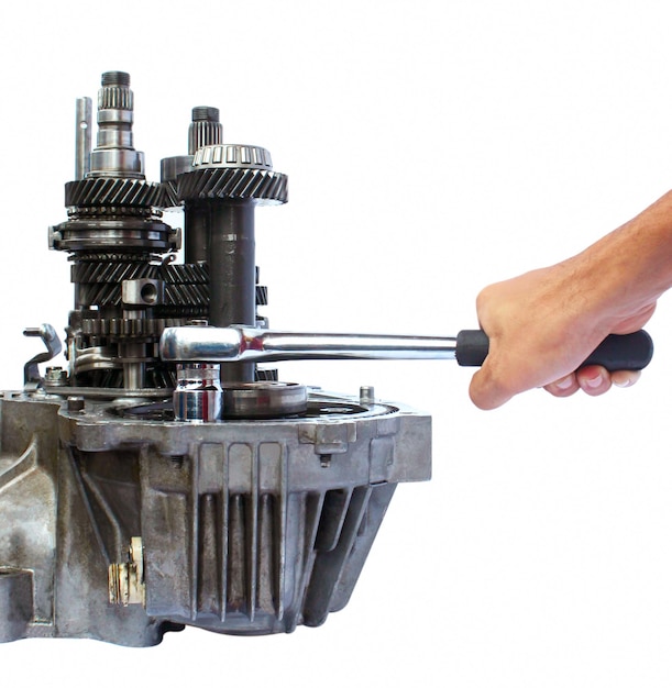 cropped hand holding wrench on engine against white background