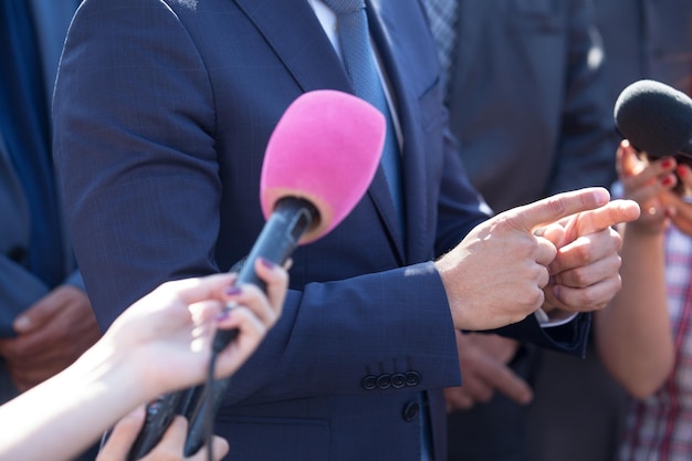 Cropped hand of journalist holding microphone in front of businessman