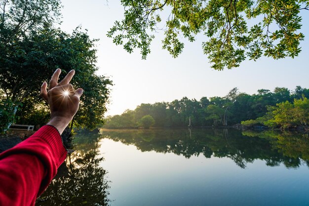 Photo cropped hand of man gesturing at sun