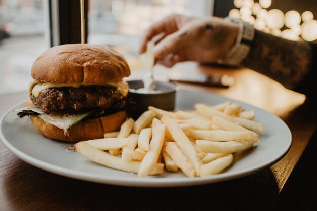 Cropped hand of man having french fries and burger in restaurant