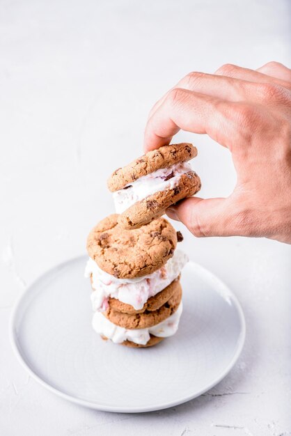 Foto mano tagliata di un uomo che mangia un panino al gelato sullo sfondo bianco