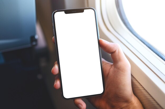 Foto mano tagliata di un uomo che tiene un telefono cellulare vuoto in aereo