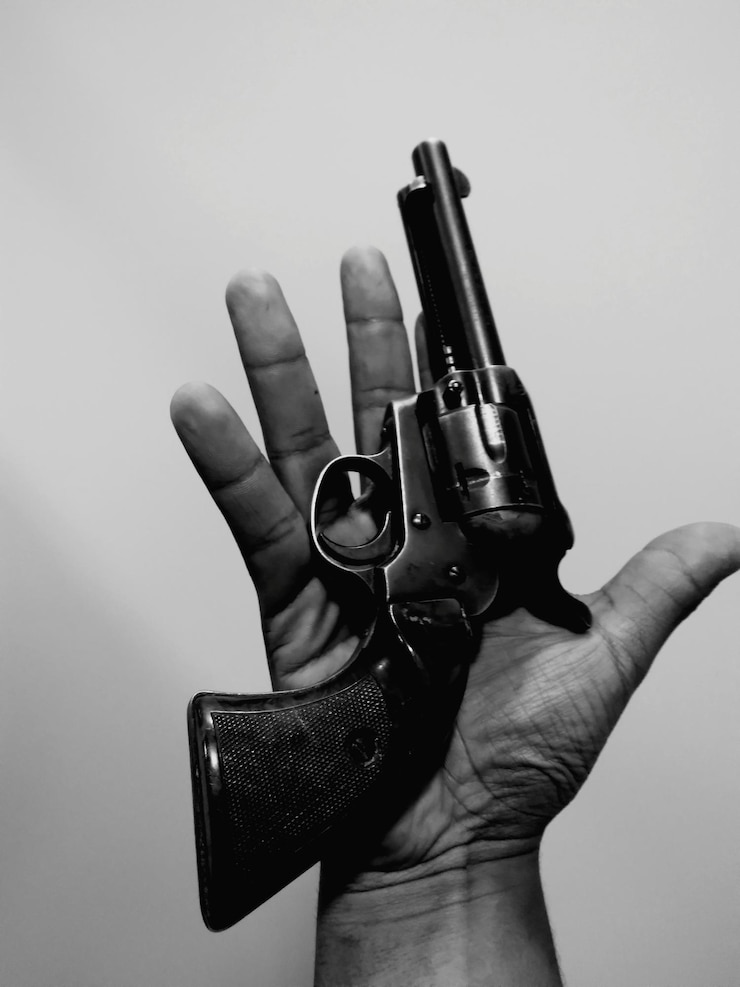 Photo cropped hand of man holding gun against white background