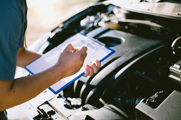 Photo cropped hand of man holding insurance document while standing by car