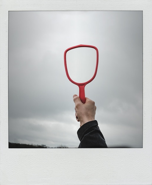 Photo cropped hand of man holding mirror against sky