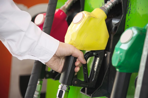 Foto mano tagliata di un uomo che tiene benzina multicolore alla stazione