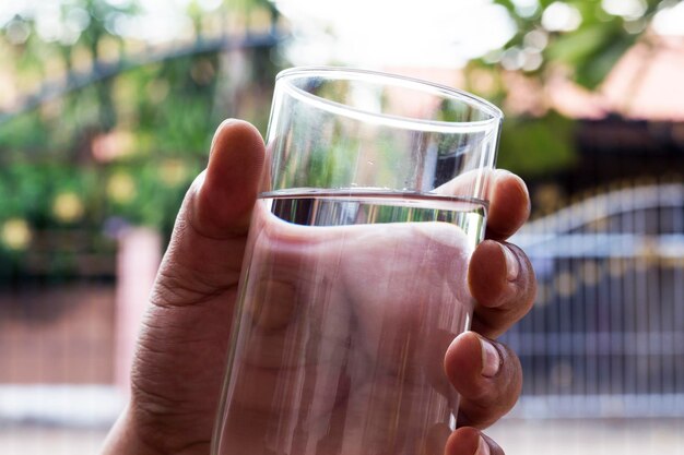 Foto mano tagliata di un uomo che tiene l'acqua in un bicchiere