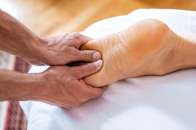 Foto mano tagliata di un uomo che massaggia il piede in una spa