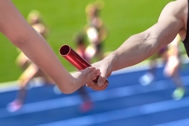 Foto mano tagliata di un uomo che passa il bastone di relè al partner