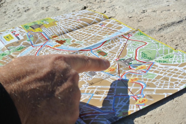 Foto mano tagliata di un uomo che indica una mappa sul pavimento