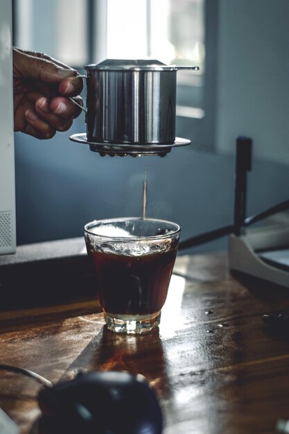 Cropped hand of man pouring coffee in glass