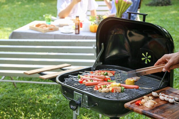 Cropped hand of man preparing food on barbecue grill