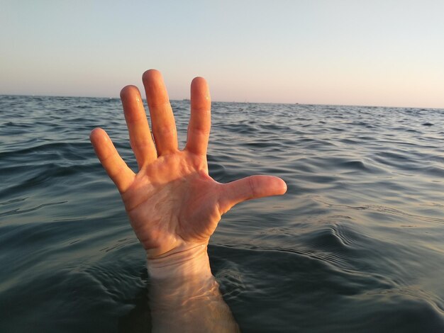 Photo cropped hand of man in sea against sky