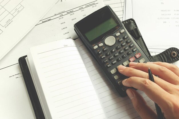 Cropped hand of man using calculator on desk at office