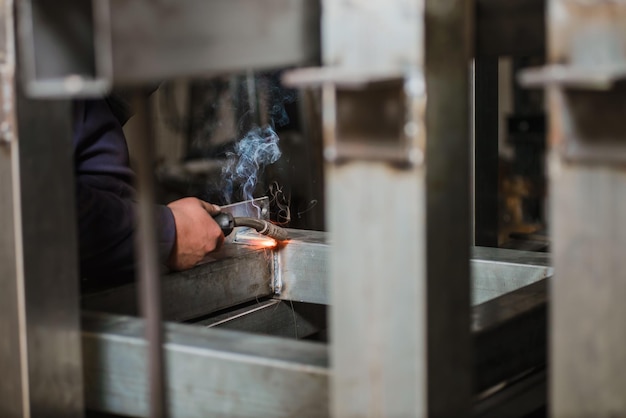 Foto mano tagliata di un uomo che salda metallo in officina