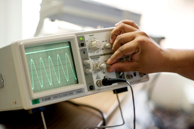 Photo cropped hand of man working on an oscilloscope in a university setting