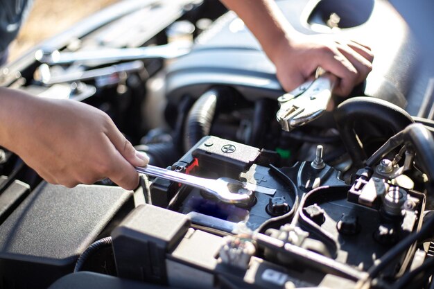 Cropped hand of mechanic repairing car engine in workshop