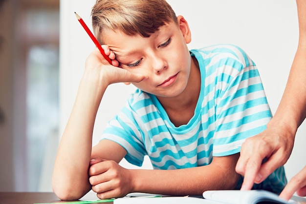 Foto mano tagliata di una madre che aiuta il figlio a studiare a casa