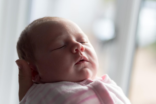 Cropped hand of mother carrying sleeping baby girl at home