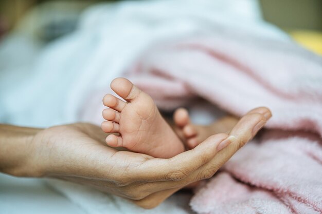 赤ちゃんの足を握っている母親の切断された手