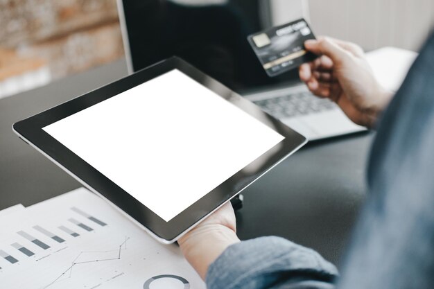 Фото Обрезка руки бизнесмена, держащего кредитную карту во время использования цифрового планшета на столе