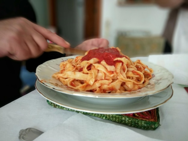 写真 テーブルの上の皿にパスタを食べている男の手を切り取った