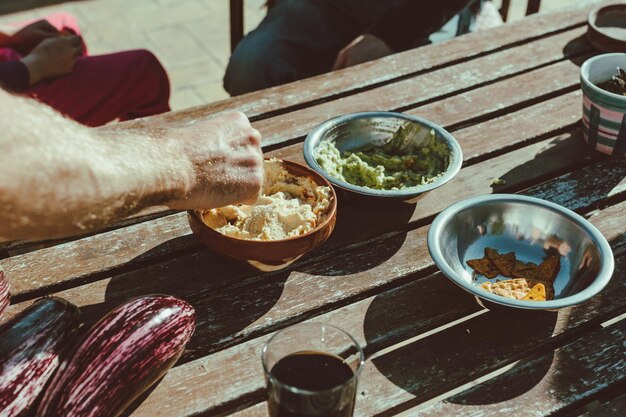 写真 木製のテーブルの上で食べ物を握っている男の手を切り取った