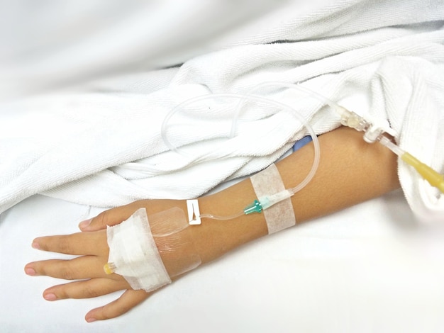 Cropped hand of patient with iv drip on bed at hospital