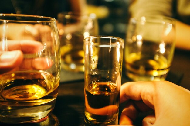 Photo cropped hand of people holding alcohol at table