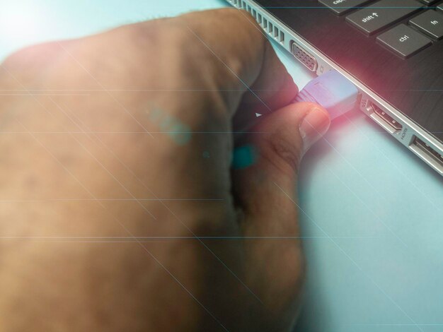 Photo cropped hand of person attaching cable to laptop on table