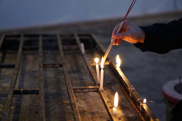 Cropped hand of person burning incense sticks with candle