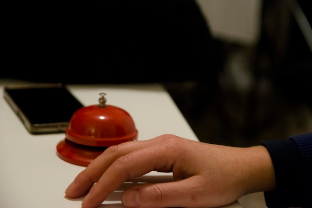 Cropped hand of person by service bell on desk