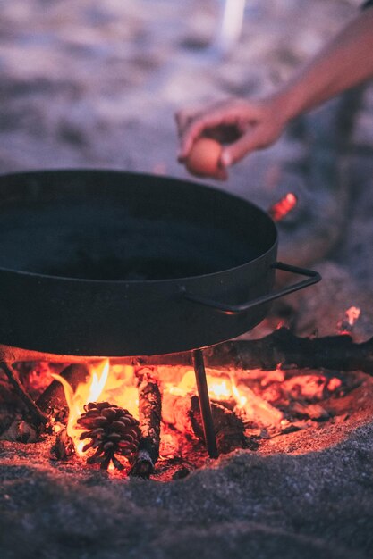 Photo cropped hand of person cooking food in pan outdoors