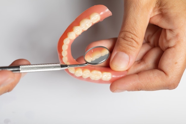 Photo cropped hand of person examining denture over white background