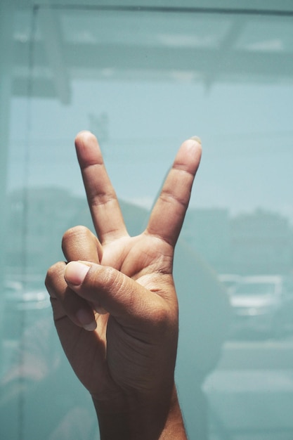 Cropped hand of person gesturing against wall