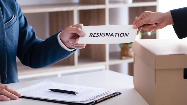 Cropped hand of person giving resignation to businessman in office