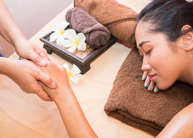 Cropped hand of person giving spa to woman on bed at home