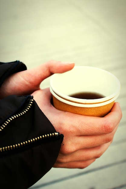 Photo cropped hand of person holding coffee in disposable cup