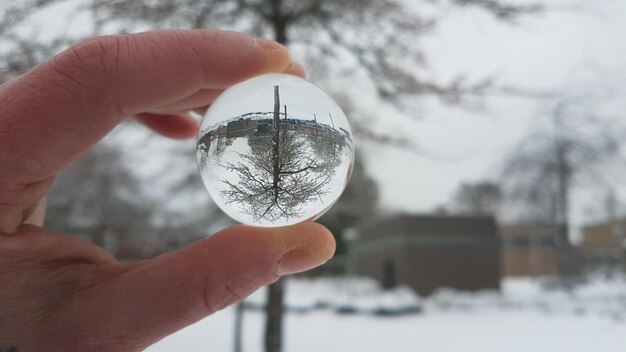 Foto mano tagliata di una persona che tiene una palla di cristallo durante l'inverno