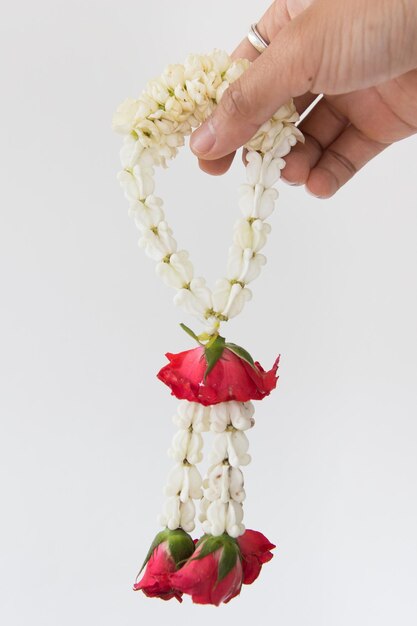 Photo cropped hand of person holding floral garland against white background