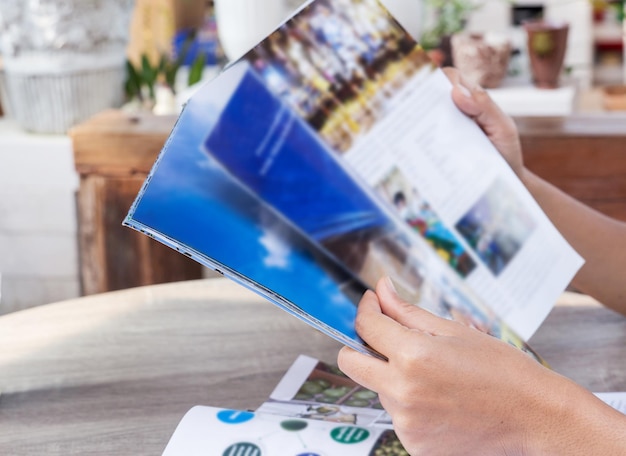 Photo cropped hand of person holding magazine on table