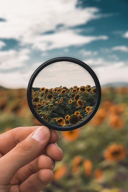 Photo cropped hand of person holding magnifying glass against sky